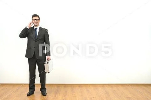 The happy businessman with a case phones on the white wall background Stock Photos
