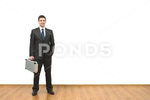 The happy businessman with a case standing on the white wall background Stock Photos