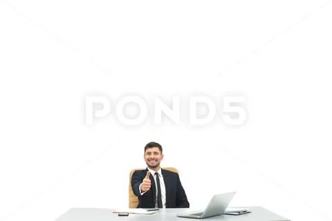 The happy businessman at the desktop thumbs up on the white background Stock Photos