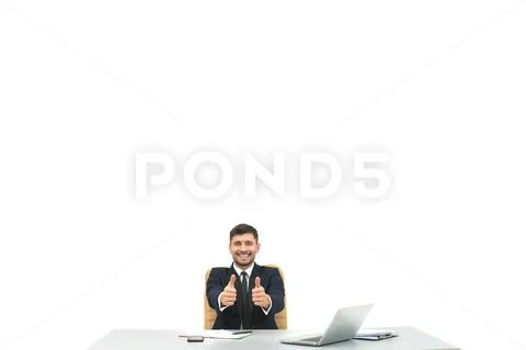 The happy businessman at the desktop thumbs up on the white background Stock Photos