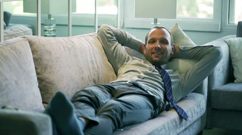Happy businessman lying on comfortable couch and smiling to the camera Stock Footage 43126604
