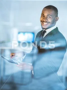 The happy businessman stand with a tablet over the office window Stock Photos