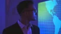 The happy businessman standing near the screen with a world map 4k or 4k+ Resolution