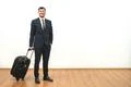 The happy businessman with a suitcase standing on the white wall background Photo