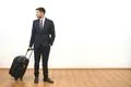 The happy businessman with a suitcase standing on the white wall background Photo