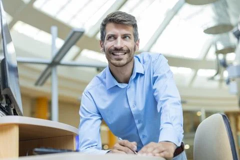 Happy businessman taking notes while working in modern office, standing by .. Stock Photos