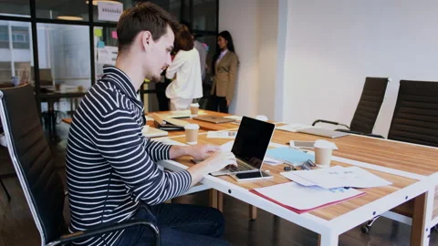 Happy businessman using laptop while coworker interacting in the background Video stock 172443835