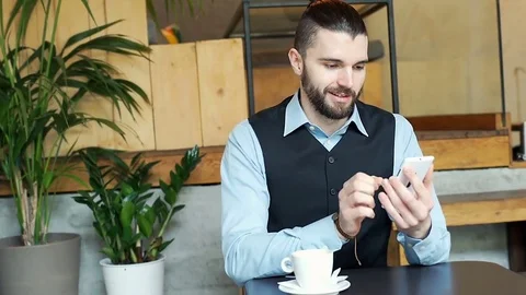 Happy businessman using smartphone in the cafe and drinking coffee, steadycam sh Stock Footage 73301155