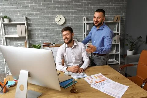 Happy businessmen with computer and documents negotiating in office Stock Photos