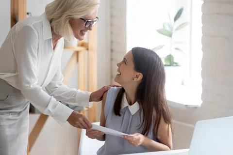 Happy businesswoman congratulate smiling female employee with promotion Stock Photos