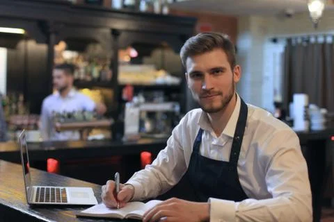 Happy cafe manager counting recipes with laptop. Stock Photos