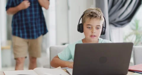 Happy caucasian boy sitting at table and using laptop for online lesson, slow Stock Footage 337096367