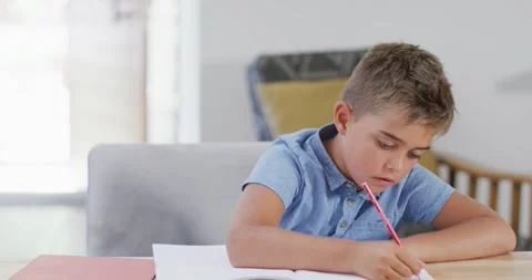 Happy caucasian boy sitting at table and doing homework, copy space, slow motion Stock Footage 343365241