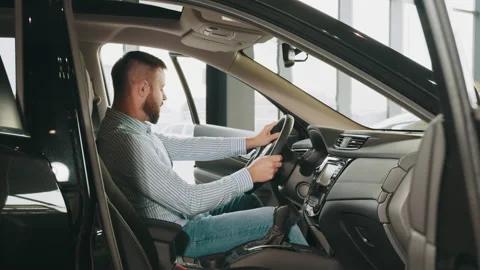 Happy caucasian man sitting inside new car and checking all function of new 動画素材 176834137