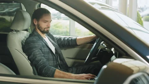 Happy caucasian man sitting inside new car and checking all function of new Stock Footage 240530134