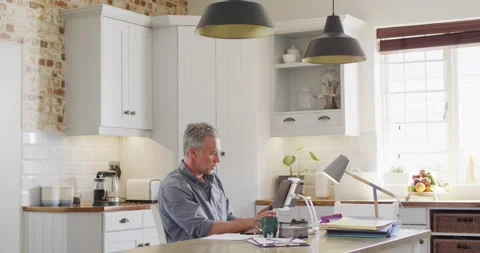 Happy caucasian man sitting at table in kitchen, using smartphone Stock Footage 337932239