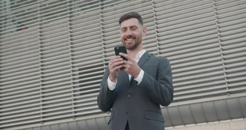 Happy Caucasian Man is using Smartphone outdoor in Business District, smiling Stock Footage 143498130