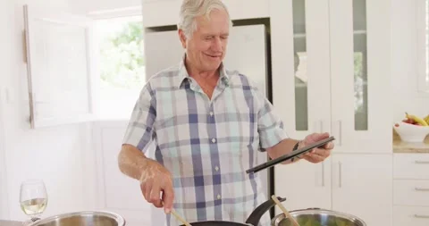 Happy caucasian senior man using tablet and cooking in kitchen Stock Footage 340971508