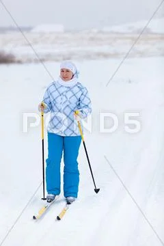 Happy caucasian woman skiing in wintry field alone Stock Photos