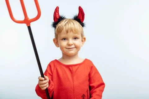 Happy cheerful boy in devil costume with trident on blue background Stock Photos
