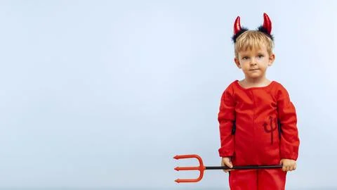 Happy cheerful boy in devil costume with trident on blue background Stock Photos