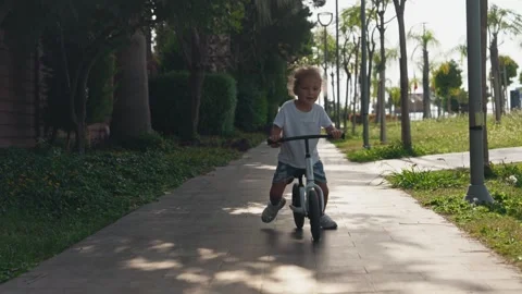 Happy cheerful child kid riding a bike in park in the nature. Little kid boy Video stock 255072653
