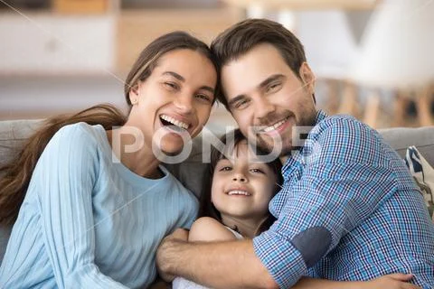 Happy cheerful family embracing sitting on couch at home Stock Photos