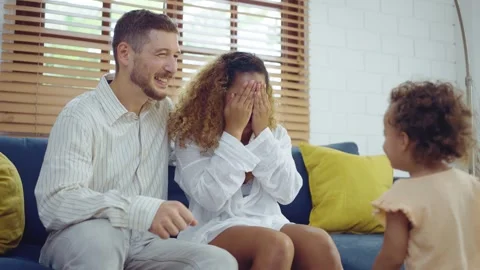 Happy cheerful parents having fun with cute daughter and hugging on sofa to.. Stock Footage 276812873