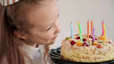 A happy child bites a big cake at a table on a light background. A funny little Video stock 192895409