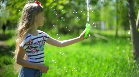 Happy child blowing soap bubbles in spring park Video stock 64331207