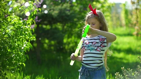 Happy child blowing soap bubbles in spring park Stock Footage 64341480
