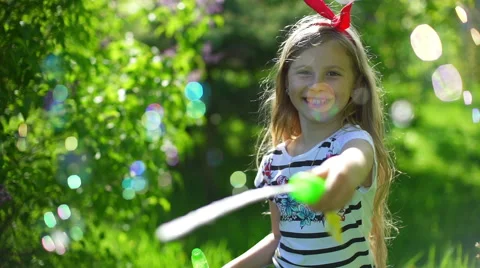 Happy child blowing soap bubbles in spring park Video stock 64341961