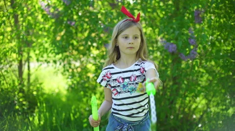 Happy child blowing soap bubbles in spring park Stock Footage 64342944
