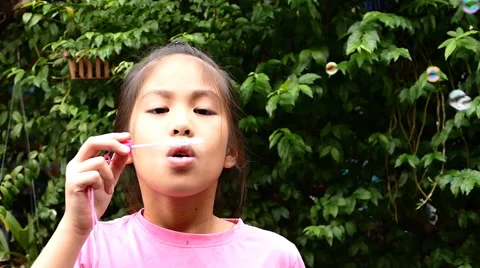 Happy child blowing soap bubbles in spring park. Slow motion Video stock 65801791