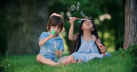 Happy child blowing soap bubbles in spring park. Slow motion Stock Footage 77551095