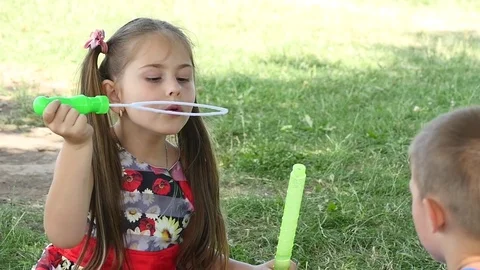 Happy child blowing soap bubbles in spring park. Slow motion Stock Footage 77742488