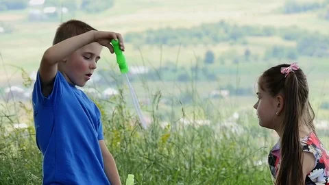 Happy child blowing soap bubbles in spring park. Slow motion Stock Footage