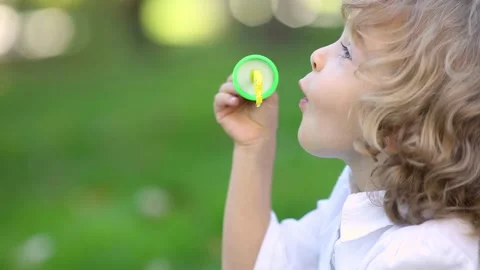 Happy child blows soap bubbles. Funny kid having fun outdoor. Little girl i.. Stock Footage 333954577