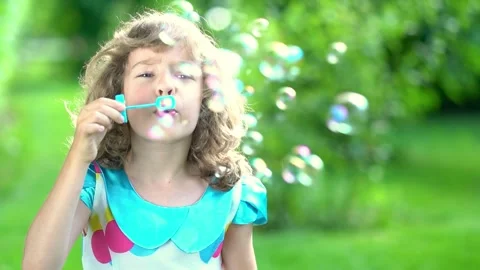 A happy child blows soap bubbles in a summer park. Slow motion Stock Footage 335826201