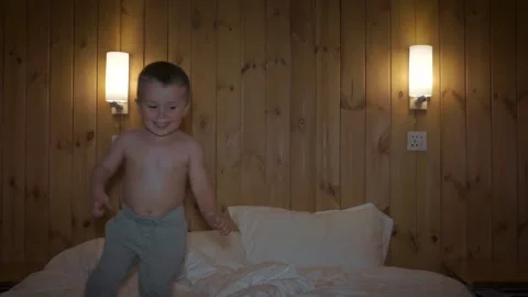 Happy child boy having fun jumps and plays on bed Stock Footage 97889943