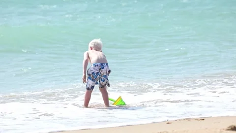 Happy child boy playing with the sand on the beach, pouring water  Stock Footage 265870052