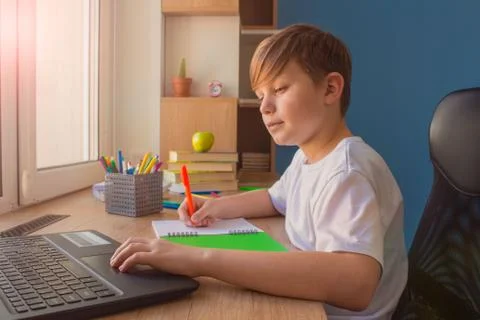 Happy child boy typing on his laptop, doing homework at home Stock Photos
