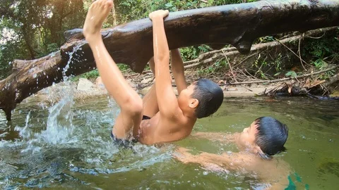 Happy child climbing falling tree in the river Video stock 125905865