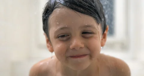 Happy child close-up face during bath time with water droplets flowing in s.. Stock Footage 250234926