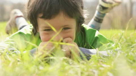 Happy child close up lay down on grass in sunny day 動画素材 64479709
