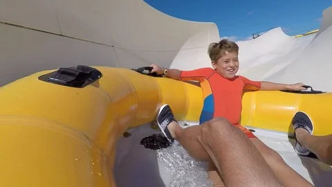 A happy child comes down excited by a slide in a water park Stock Footage