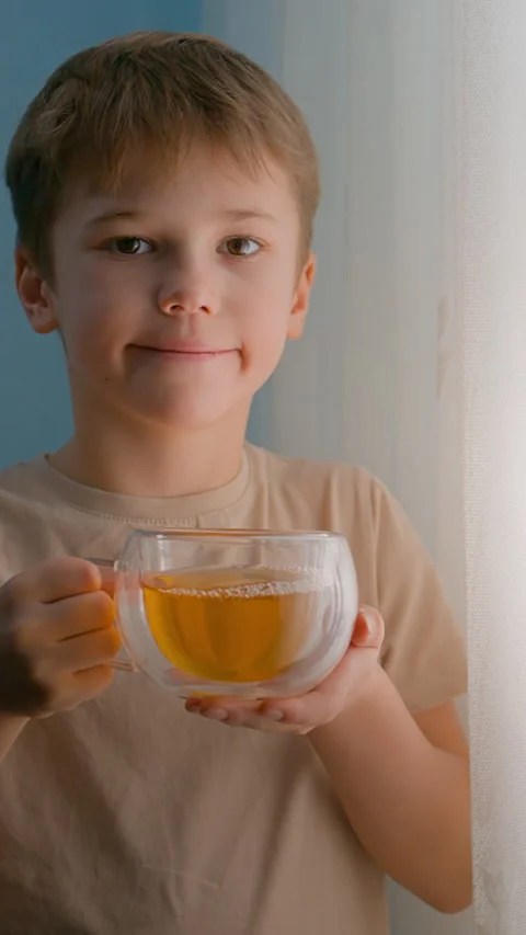Happy child drinking herbal tea from a transparent glass cup Video stock 326165155