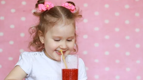 A happy child is drinking smoothies through a straw and smiling. Close-up Stock Footage 89321010