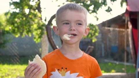 A happy child eats bread. Child's smile. A child has bad teeth. White bread in a 스톡 동영상 201082420