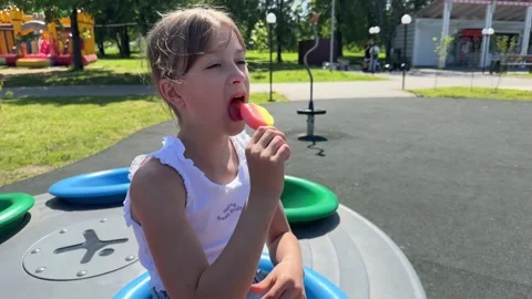 A happy child eats ice cream while relaxing in the park on a summer day, Stock Footage 244326409